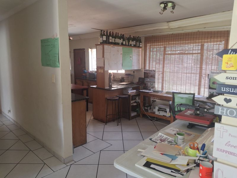 Open plan living and kitchen area featuring tiled flooring, built-in cabinetry, and a breakfast bar, currently utilized as a workspace.