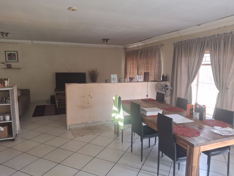Open plan living and dining area featuring ceramic floor tiles and a central partition wall, offering a versatile layout for family living.
