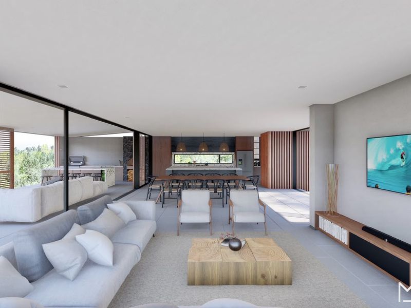 A modern open-plan living and kitchen area featuring large sliding glass doors, sleek cabinetry, and a seamless transition to an outdoor patio space.