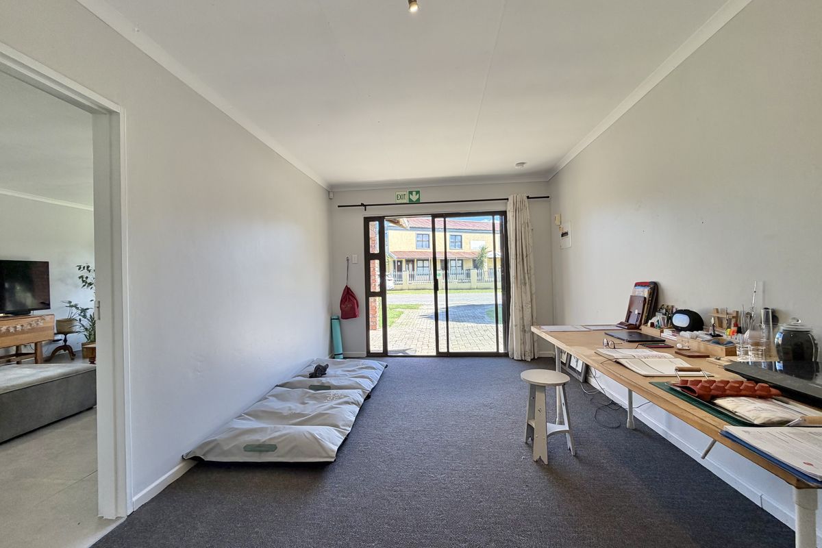 A spacious living area featuring neutral walls, carpeted flooring, and a large sliding glass door providing direct access to the exterior.