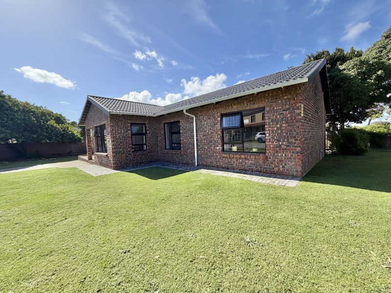 A well-maintained face brick house exterior featuring a tiled roof, aluminium window frames, and a neat surrounding lawn with paved pathways.