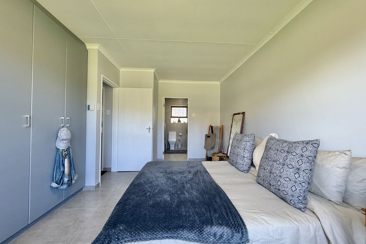 A well-maintained bedroom featuring neutral tiled flooring, ample built-in cupboard space, and direct access to an en-suite bathroom.