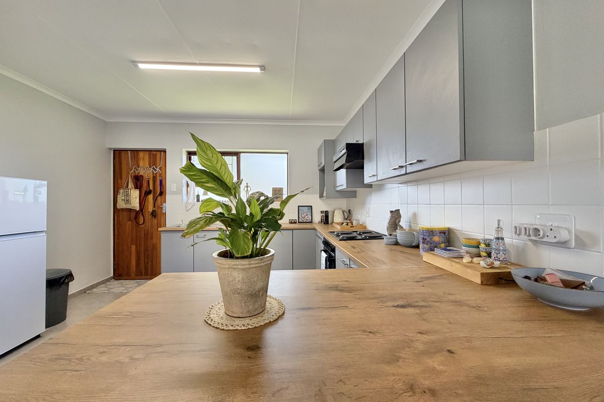 A modern kitchen featuring grey cabinetry, wood-look laminate countertops, a tiled backsplash, and integrated appliances, offering a clean and functional workspace.