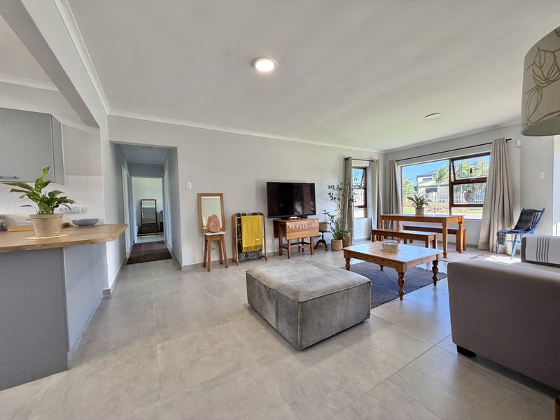 Spacious open-plan living and dining area featuring neutral tiled flooring, modern kitchen cabinetry, and large windows providing ample natural light.