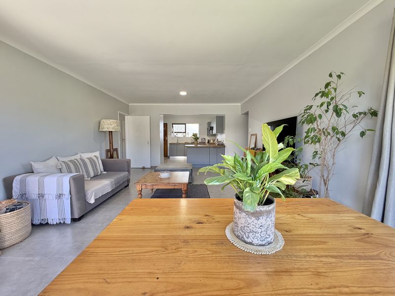 An open-plan living area featuring tiled flooring and a seamless transition to a functional kitchen with modern cabinetry and a central island.