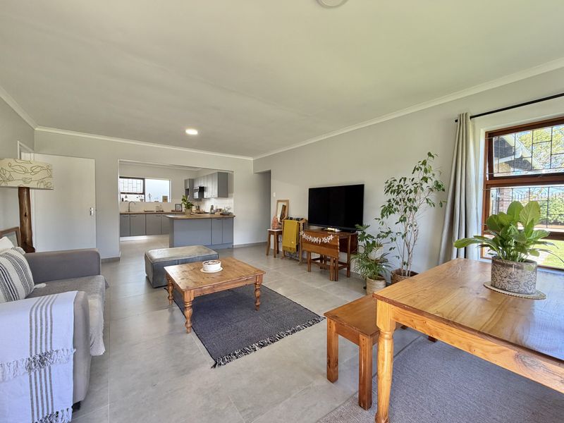 Spacious open-plan living area featuring neutral tiled flooring, recessed lighting, and a modern kitchen with grey cabinetry and a central island.
