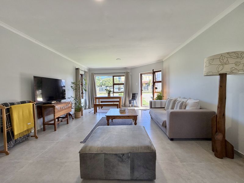 Spacious open-plan living and dining area featuring neutral tiled flooring, large windows, and direct access to the exterior.