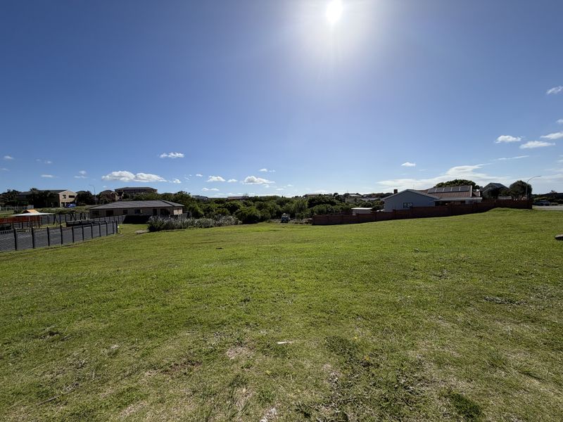 A wide-angle view of a vacant residential plot featuring a well-maintained grass lawn and surrounding boundary fencing in a quiet neighborhood.