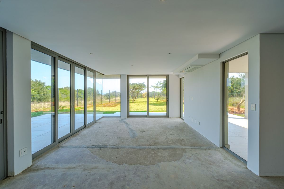 Spacious, light-filled living area featuring floor-to-ceiling glass doors with direct access to the patio and garden, currently awaiting final flooring installation.