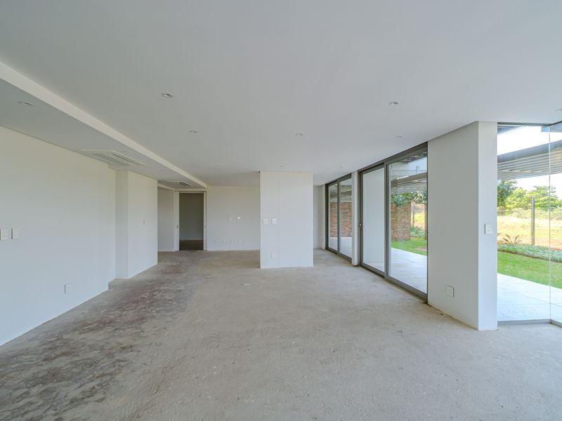 Spacious open-plan living area featuring large sliding glass doors, recessed lighting, and ducted air conditioning, currently awaiting final flooring installation.