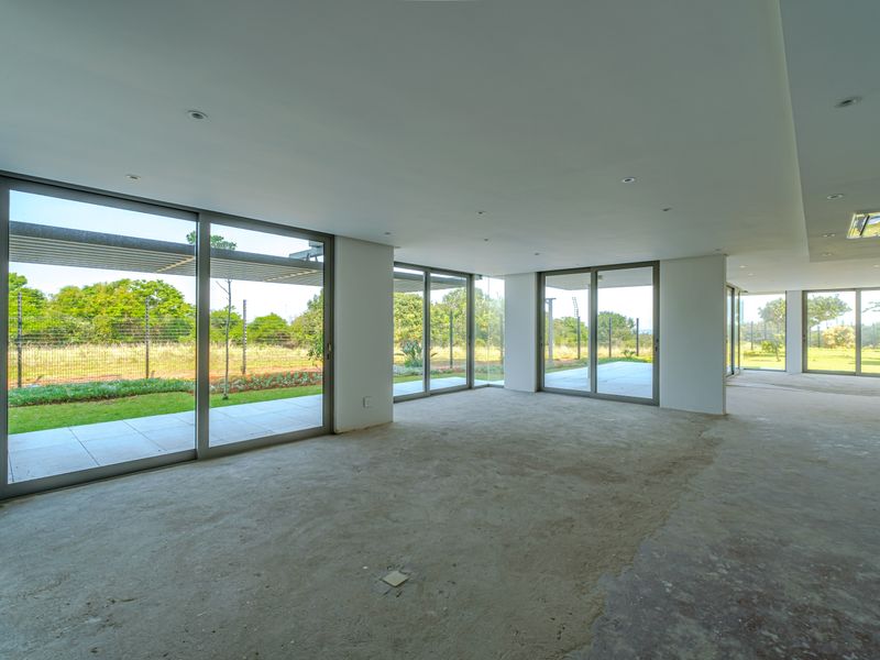 Spacious open-plan living area featuring large sliding glass doors, recessed lighting, and unfinished concrete flooring, offering a blank canvas for custom interior design.