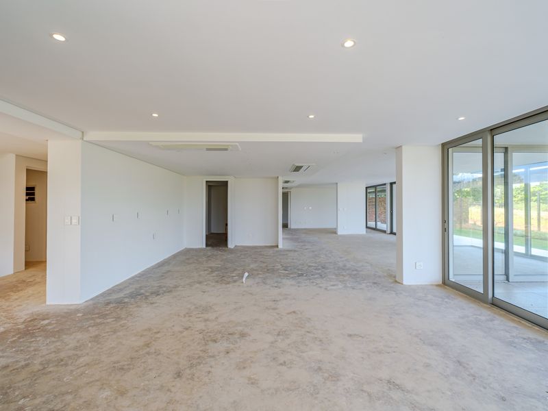 Spacious open-plan living area featuring concrete flooring, recessed lighting, ducted air conditioning, and large aluminium sliding doors leading to the exterior.