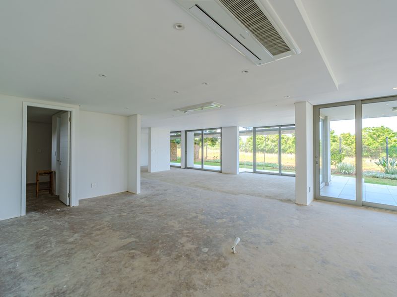 Spacious open-plan living area featuring ducted air conditioning, recessed lighting, and large sliding glass doors leading to the outdoor patio.
