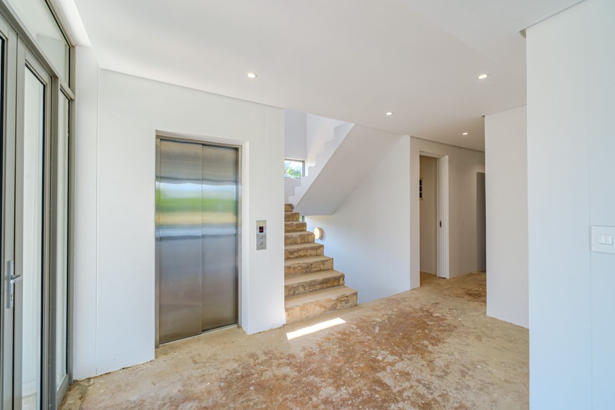 Entrance foyer featuring a private elevator and staircase, currently in an unfinished state awaiting final flooring and stair finishes.