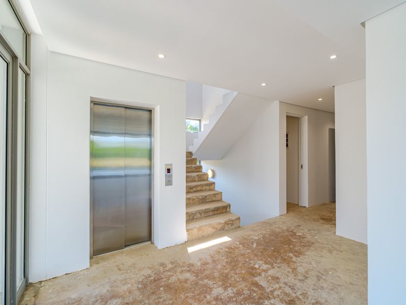 Entrance foyer featuring a private elevator and staircase, currently in an unfinished state awaiting final flooring and stair finishes.