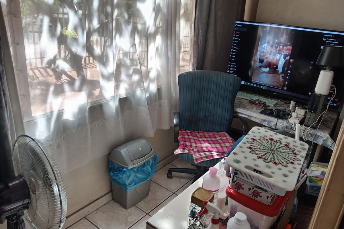A living area featuring tiled flooring and a large window providing natural light, suitable for a comfortable seating or workspace arrangement.