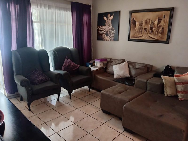 A comfortable living room area featuring tiled flooring and a large window with curtains, providing a bright and functional space.