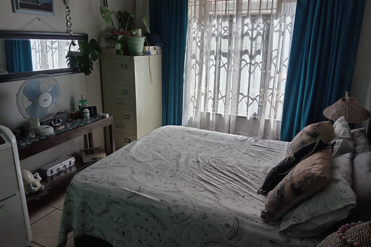 A bedroom featuring tiled flooring and a window fitted with a security gate, providing natural light and ventilation.