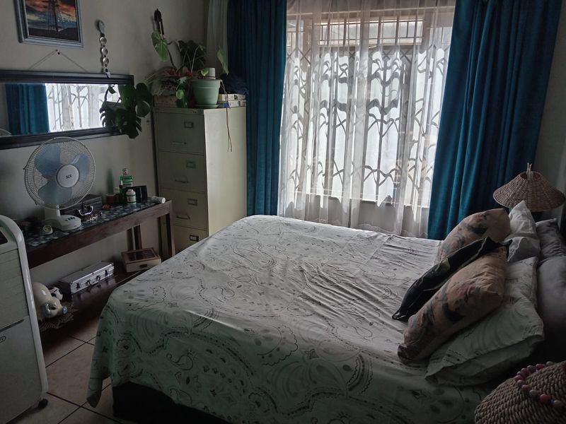 A bedroom featuring tiled flooring and a window fitted with a security gate, providing natural light and ventilation.