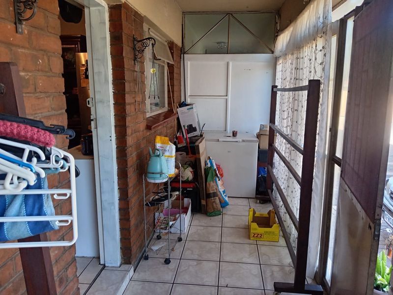A covered patio area featuring exposed brick walls and tiled flooring, providing a functional transition space between the interior and exterior of the property.