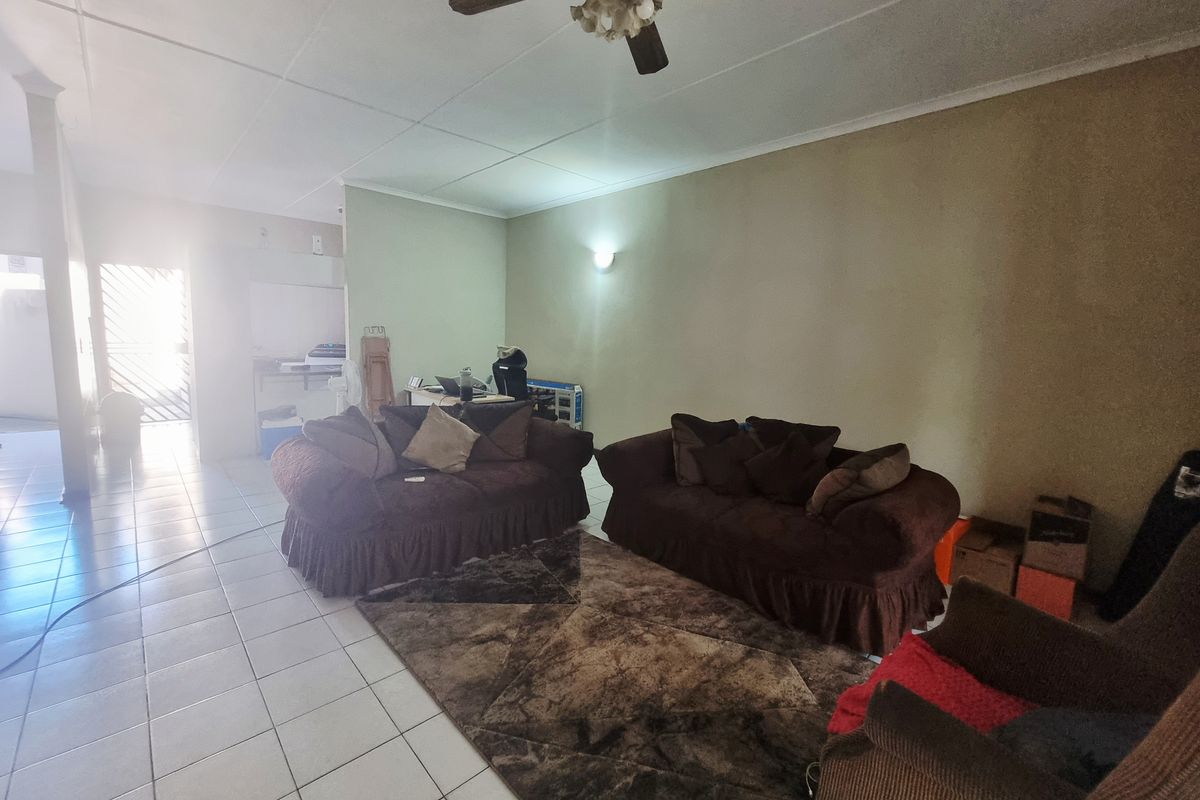 Spacious living area featuring tiled flooring, a ceiling fan, and neutral wall tones, offering a blank canvas for modern interior updates.