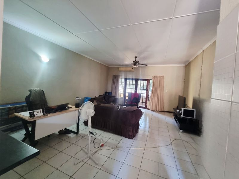 Spacious living area featuring tiled flooring, a ceiling fan, and split-system air conditioning, with direct access to an outdoor area through glass sliding doors.