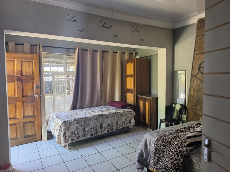 A bedroom featuring tiled flooring, a stone accent wall, and direct access to an outdoor area through a wooden door and security gate.