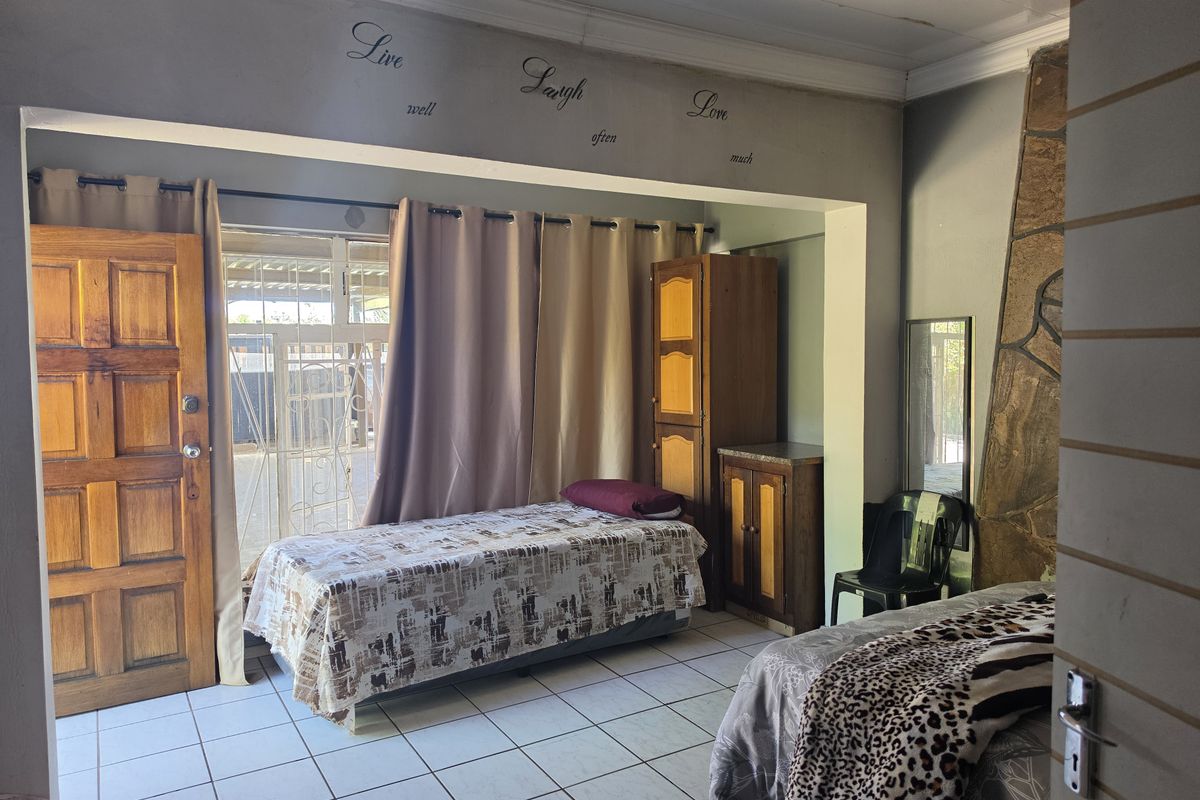 A bedroom featuring tiled flooring, a stone accent wall, and direct access to an outdoor area through a wooden door and security gate.