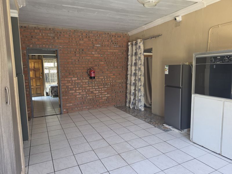 Open plan living area featuring exposed brickwork, ceramic tiled flooring, and a built-in oven, offering a functional space with potential for modernization.