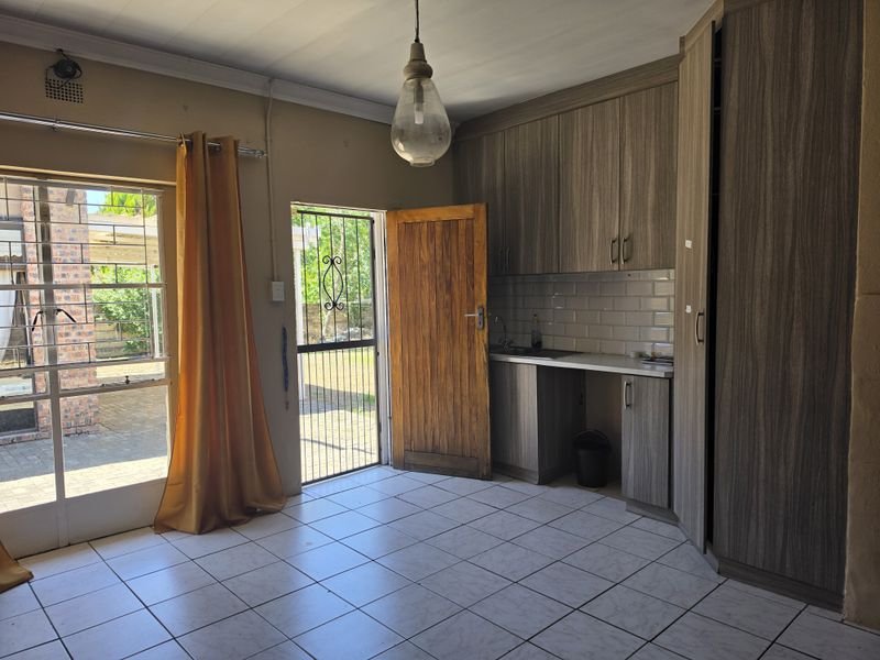 A functional kitchen area featuring built-in cabinetry, subway tile backsplash, and direct access to the exterior through a security gate.