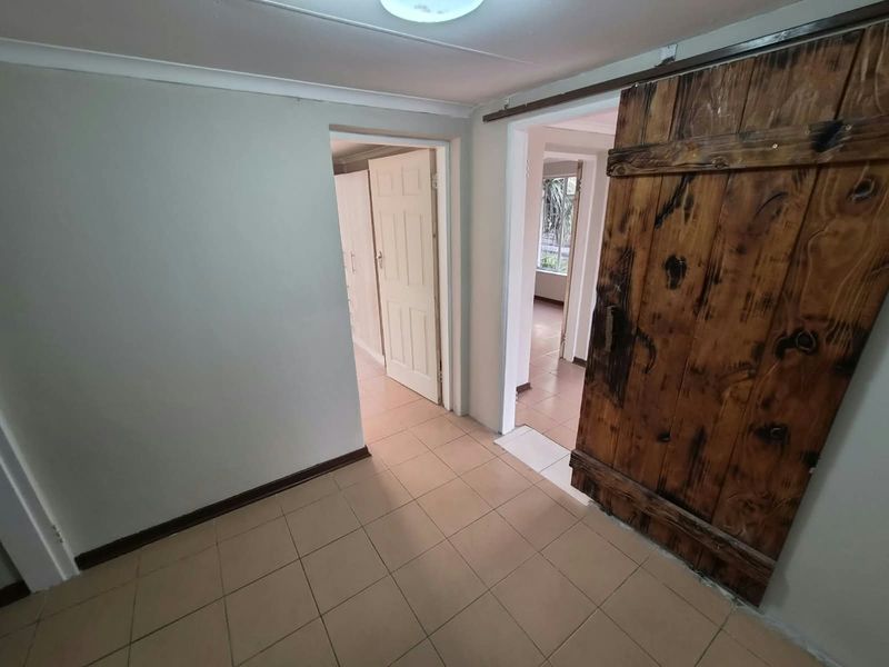 A functional hallway featuring tiled flooring and a rustic sliding barn door, providing access to adjacent rooms within the apartment.