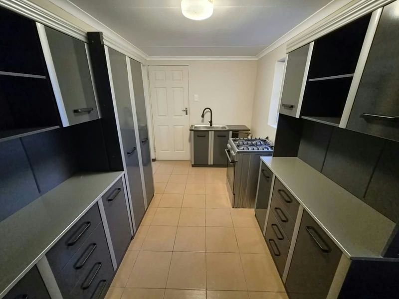A functional kitchen featuring ample built-in cabinetry, a gas stove, and tiled flooring, offering a clean and practical workspace.