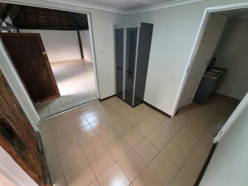 A functional hallway area with tiled flooring, providing access to adjacent rooms including a living space and a small kitchenette area.