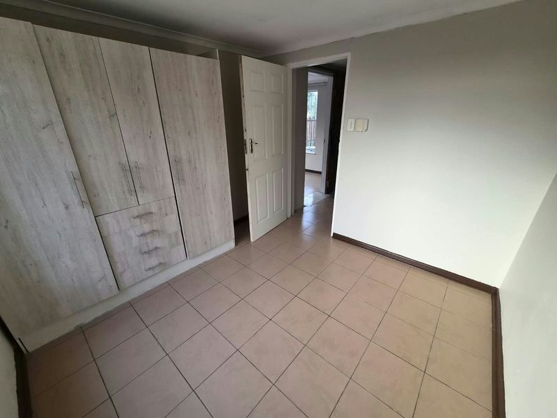 An empty bedroom featuring built-in cupboards and tiled flooring, offering a neutral space ready for personalization.