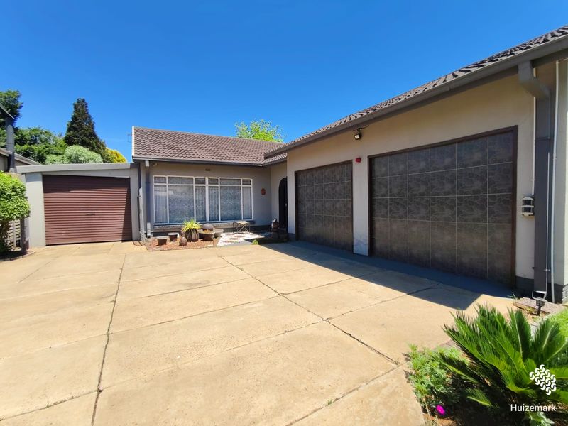 Front exterior view of the property featuring a concrete driveway, a double garage with tiled doors, and an additional single garage.