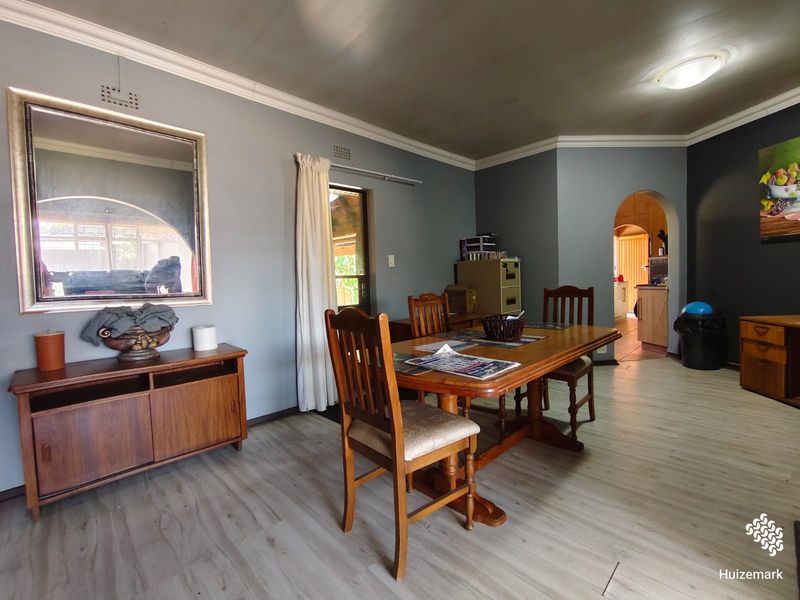 A dining room featuring light-toned laminate flooring, crown molding, and an arched entryway leading to an adjacent space.