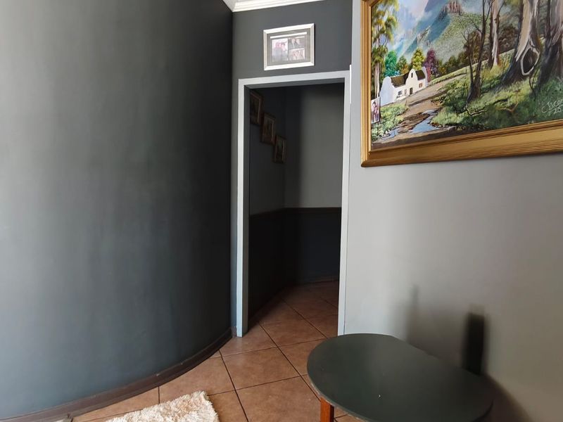 A well-maintained hallway featuring a distinctive curved wall, decorative crown molding, and durable tiled flooring leading into an adjacent room.