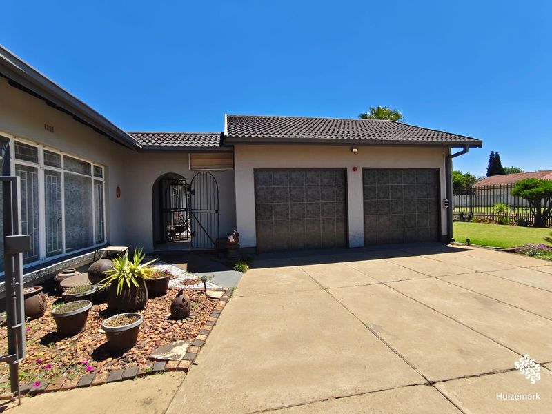 Front exterior view of the property featuring a double garage, concrete driveway, and a secure arched entrance.