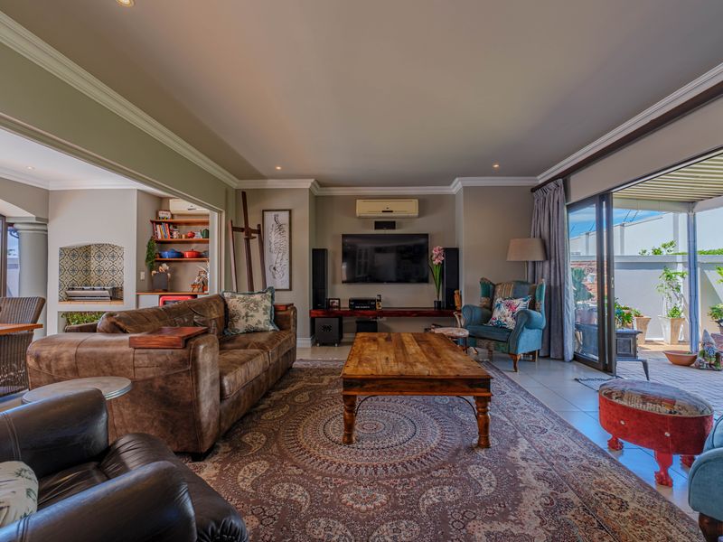 Spacious open-plan living area featuring tiled floors, crown molding, recessed lighting, and seamless access to an outdoor patio through large sliding glass doors.