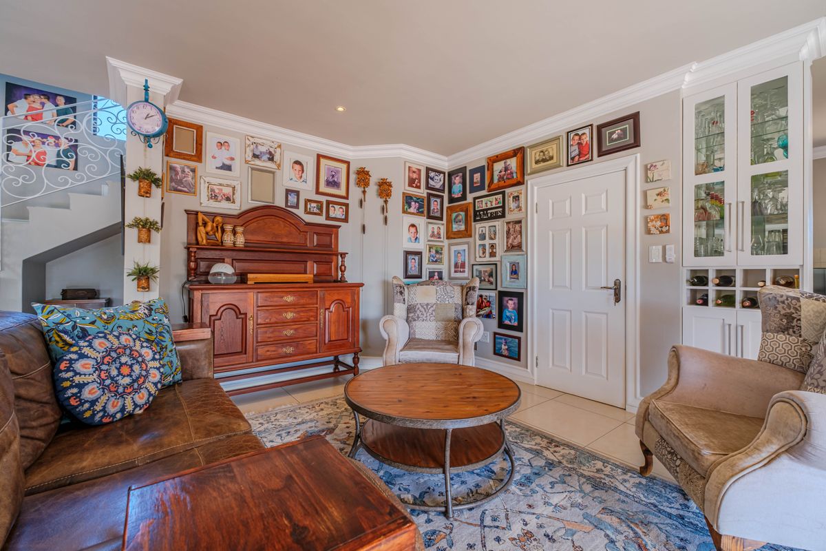 A cozy living room featuring tiled flooring, crown molding, a wrought iron staircase, and built-in display cabinetry.