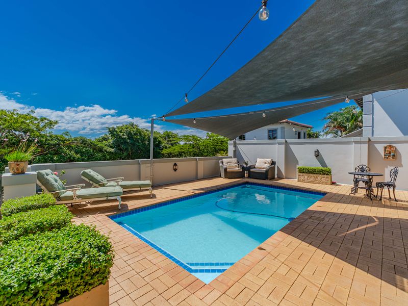 A well-maintained outdoor pool area featuring a paved deck, perimeter wall, and a shade sail, perfect for relaxation and outdoor entertainment.