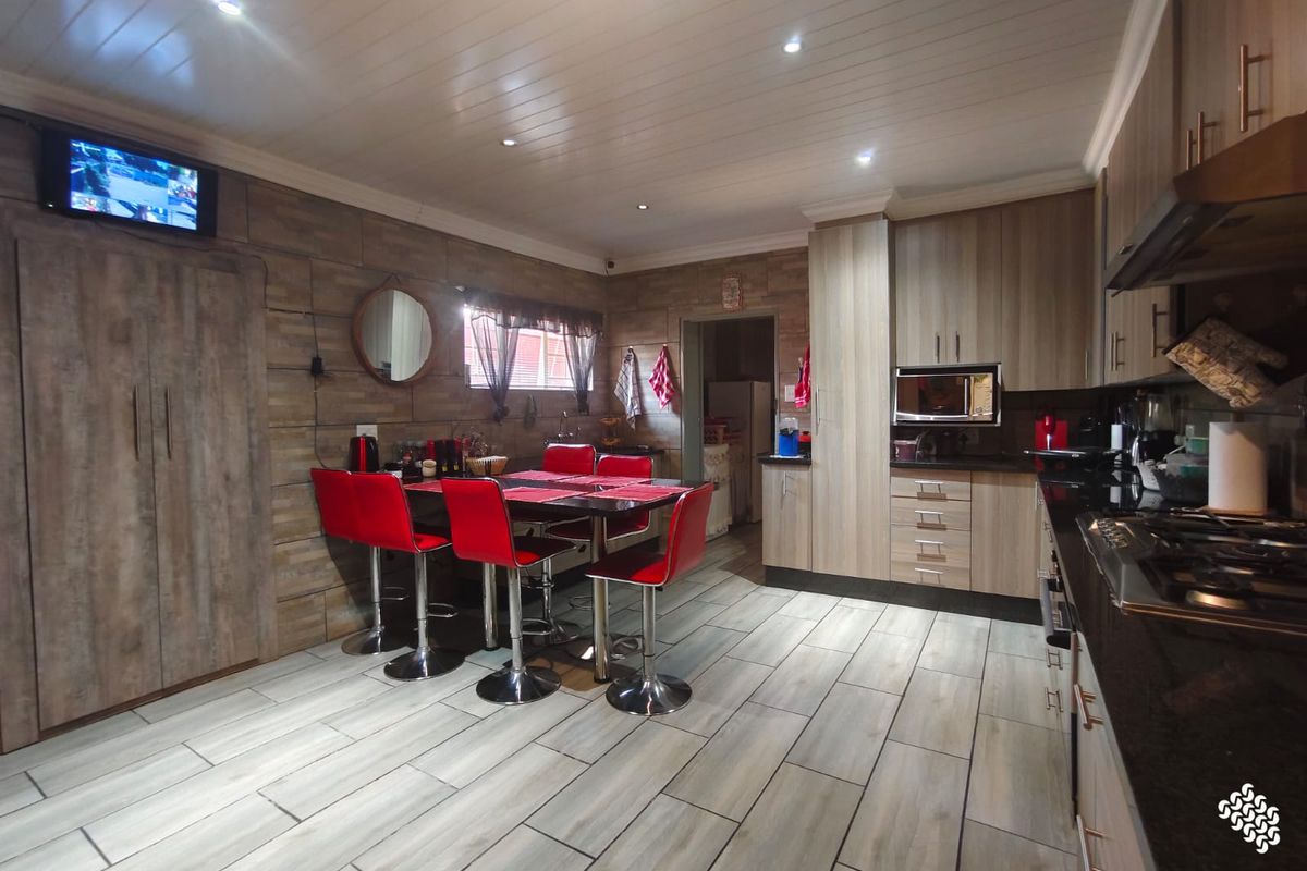 Modern kitchen featuring wood-look cabinetry, granite countertops, gas hob, and integrated appliances, complemented by tiled flooring and recessed ceiling lighting.