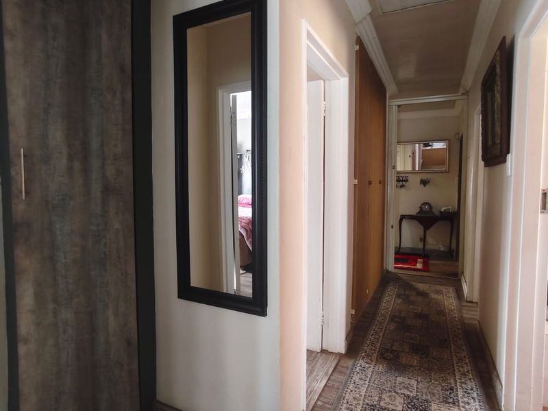 A functional hallway featuring built-in storage cupboards, ceiling cornicing, and access to the loft area, connecting various rooms within the home.