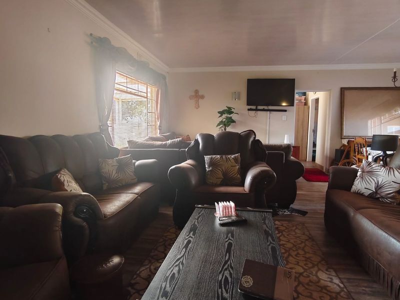 A comfortable living room featuring a coved ceiling and venetian blinds, providing a functional and lived-in space for relaxation.