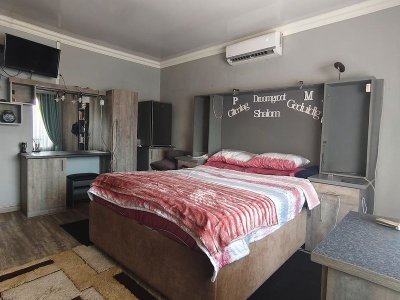 A bedroom featuring built-in cabinetry, a vanity unit, and a split-system air conditioner, finished with laminate flooring.