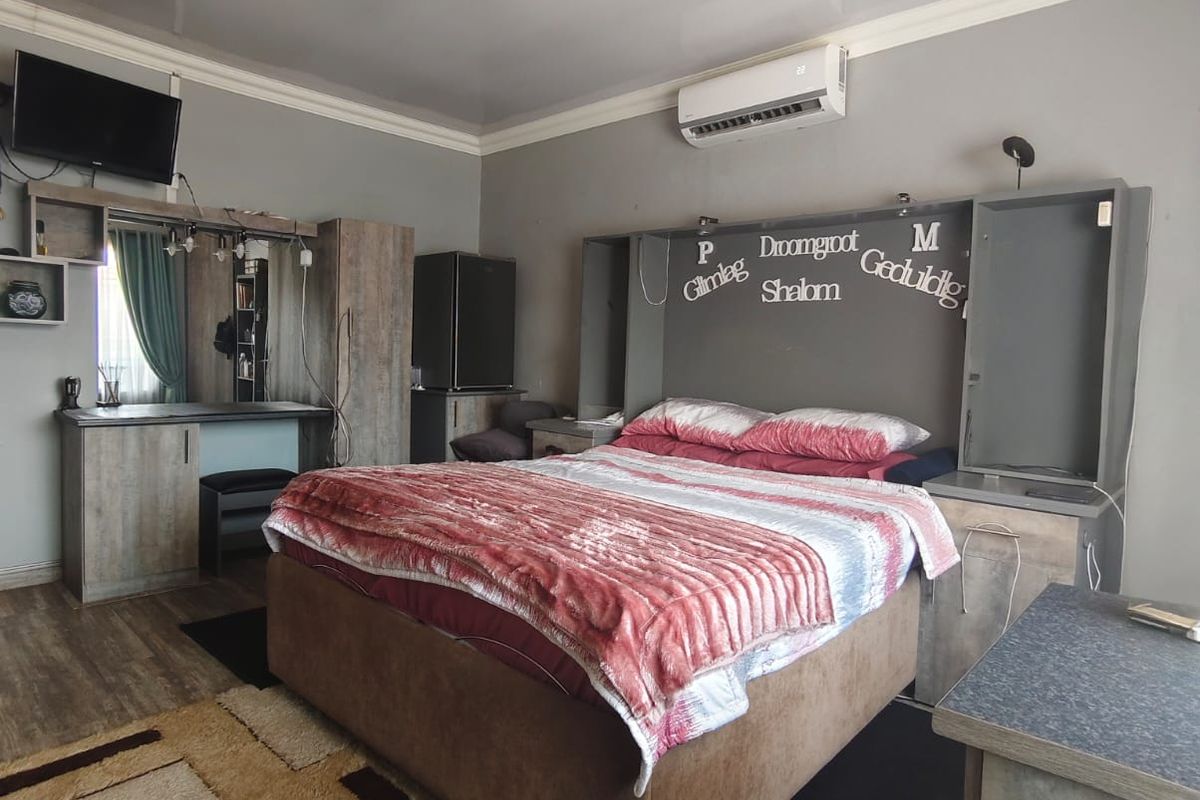 A bedroom featuring built-in cabinetry, a vanity unit, and a split-system air conditioner, finished with laminate flooring.