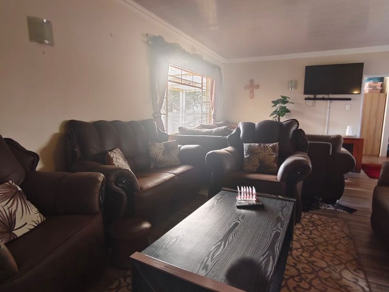 A comfortable living room featuring coving, venetian blinds, and a wall-mounted television bracket, offering a functional space for relaxation.