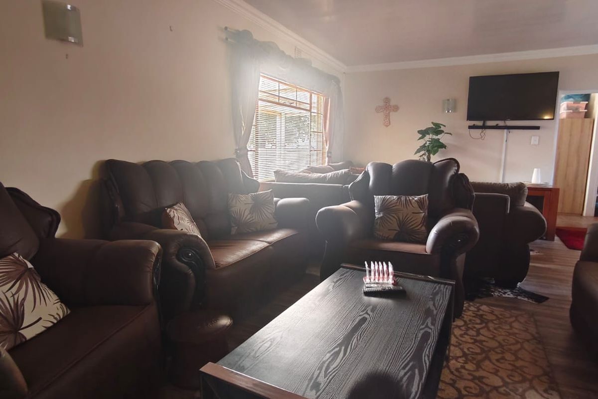 A comfortable living room featuring coving, venetian blinds, and a wall-mounted television bracket, offering a functional space for relaxation.