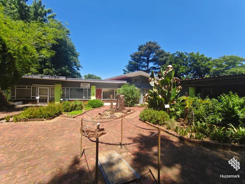Front exterior view of a single-story house featuring a brick-paved courtyard, security bars on windows, and established garden landscaping.