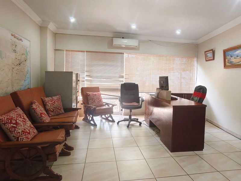 A functional office space featuring tiled flooring, recessed downlighting, and wall-mounted air conditioning, providing a practical environment for professional use.